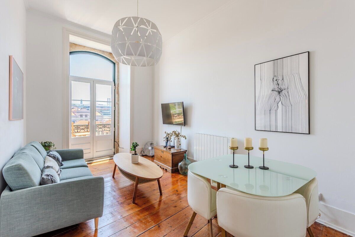 Una sala de estar moderna con un sofá, una mesa de comedor de vidrio con velas, un televisor y una obra de arte enmarcada en la pared.