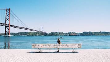 A bench by a waterfront with a bridge in the background.