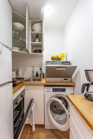 Eine kompakte Küche mit Backofen, Waschmaschine und Toaster.