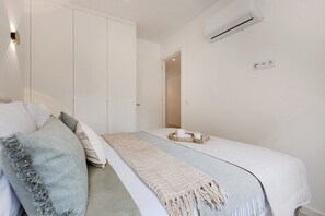 Ein Schlafzimmer mit einem Bett, einem Nachttisch mit Kerzen, einem Kleiderschrank und einer Klimaanlage.