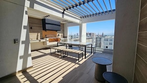 Ein moderner Balkon mit Fernseher, Holzboden und Blick auf die Stadt.