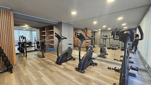 Ein Fitnessstudio mit unterschiedlichen Trainingsgeräten, darunter Laufbänder und Ergometer, sowie einer Spiegelwand.