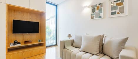 A modern living room with a flat-screen TV, a sofa, and abstract wall art.