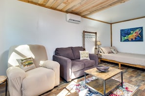 Ein gemütliches Zimmer mit einer Couch, einem Sessel, einem kleinen Tisch und einem Bett.
