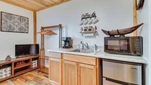 A compact kitchen with wooden cabinets, a microwave, a coffee maker, and a TV. - 3 Studio Suites! White River Cabin Compound (Norfork)