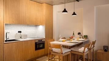 Cozinha moderna com armários de madeira, forno embutido, pia e área de jantar com mesa e cadeiras.