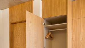 Ein Holzkleiderkasten mit mehreren Einlegeböden und einer Kleiderstange.