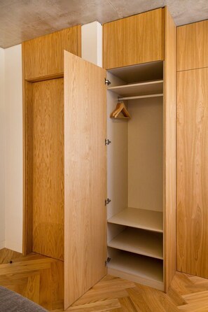 A wooden wardrobe with multiple shelves and a hanging space. - Design 2BR in Campo de Ourique (Lisbon)