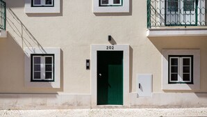 Ein Gebäude mit grüner Tür, Hausnummer 202, und einem kleinen Fenster zur rechten Seite.