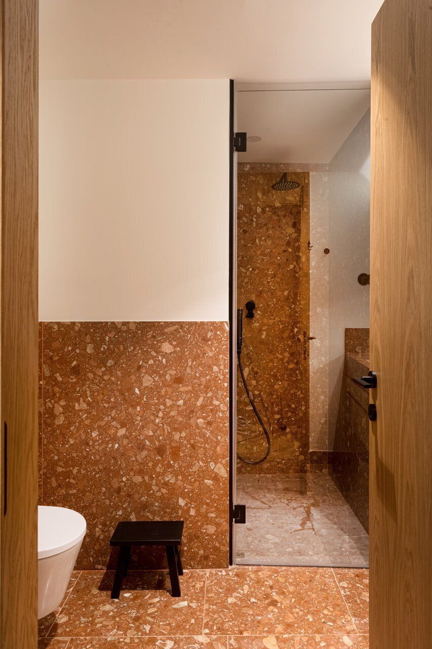 Ein Badezimmer mit Dusche, Toilette und einem kleinen Hocker.