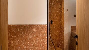 Ein Badezimmer mit Dusche, Toilette und einem kleinen Hocker.