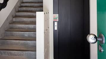 Escada que leva a uma porta com puxador de metal, um armário branco e um chão de terrazzo.