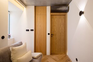 Ein Zimmer mit Holzschrank, einer Couch mit Kissen und einer Wandleuchte.