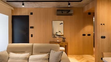 Una habitación moderna con sofá, paneles de madera, un espejo y una lámpara en el techo.