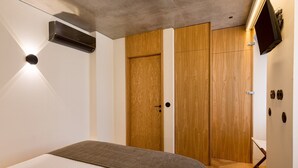 Ein Schlafzimmer mit Bett, Kleiderschrank, Fernseher und Heizung.