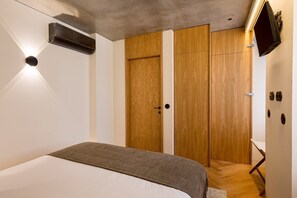 A bedroom with a bed, a wardrobe, a television, and a heater. - Design 2BR in Campo de Ourique (Lisbon)