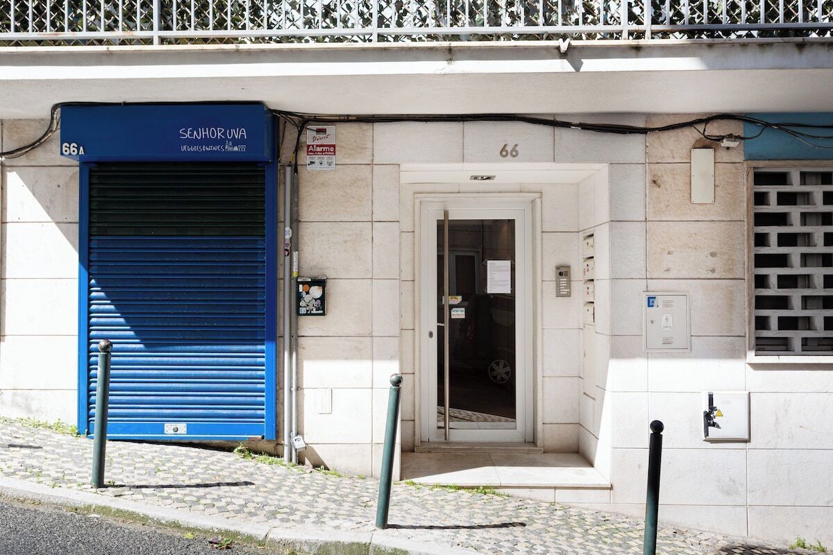A building with a blue shuttered entrance, a door with a sign, and a number '66' on the wall.