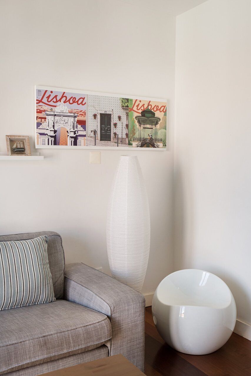 Una sala de estar con un sofá, una mesa redonda blanca y un jarrón blanco alto.