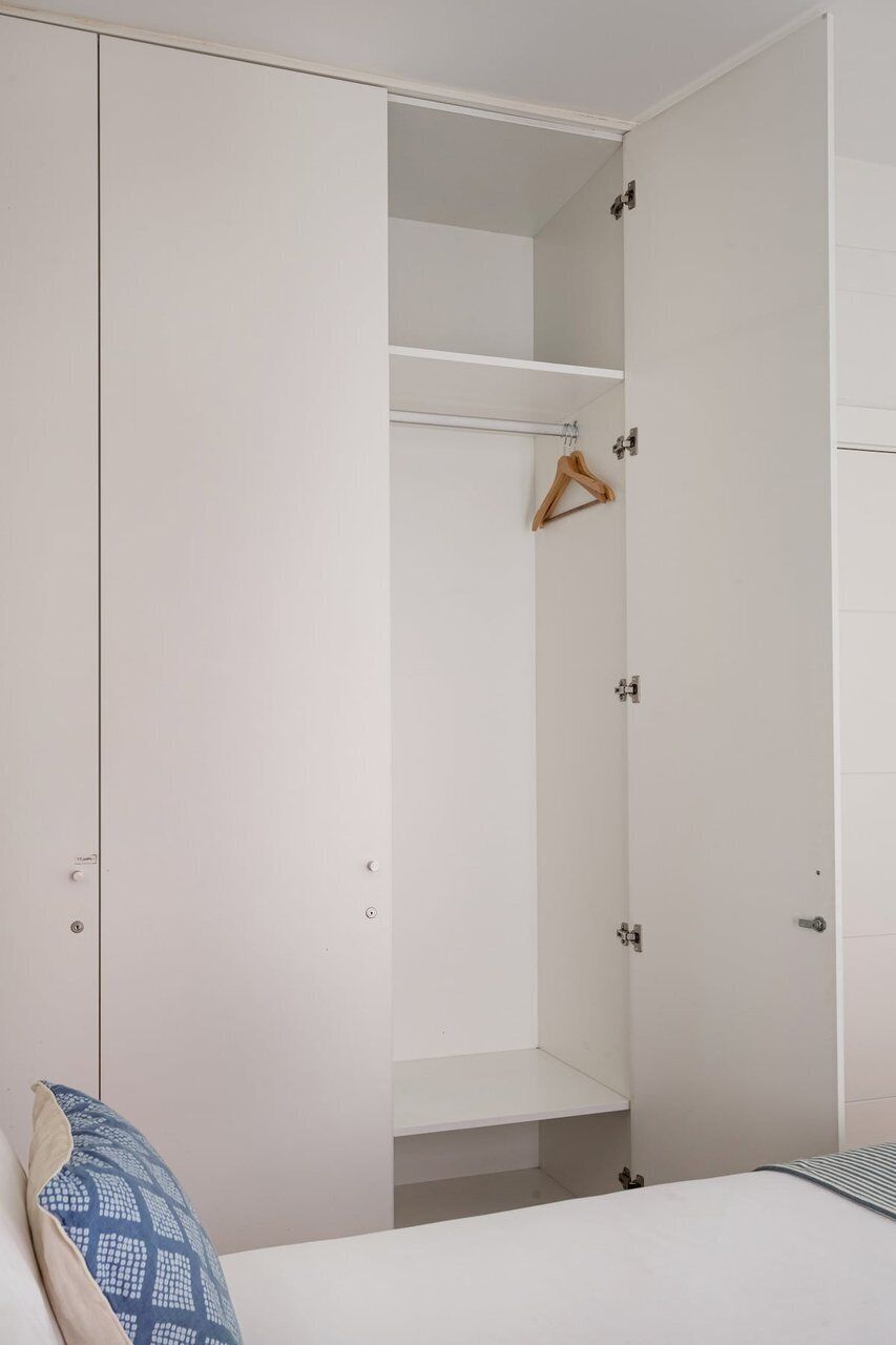 A bedroom with a bed, a wardrobe, and a hanging rack.