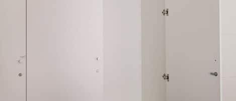 A bedroom with a bed, a wardrobe, and a hanging rack.