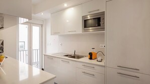 Een moderne keuken met witte kasten, een roestvrijstalen spoelbak en een ingebouwde magnetron.