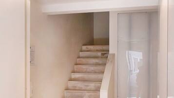 A staircase with marble steps, a handrail, and two ceiling lights.