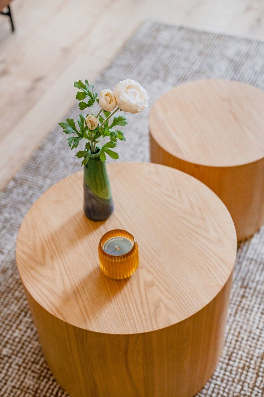 Une table ronde en bois, ornée d’un vase de fleurs et d’une bougie.