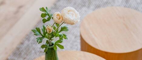 A round wooden table with a vase of flowers and a candle.