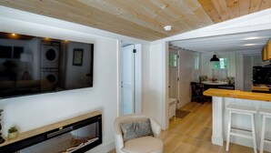 Un salon avec un téléviseur, une cheminée et un plafond en bois.