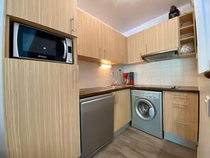 A compact kitchen with a microwave, dishwasher, and washing machine. - 100m from ski slopes, 2nd floor, jacuzzi, hammam, terrace, parking, tv, ski locker, 51m², Peyragudes (Germ)