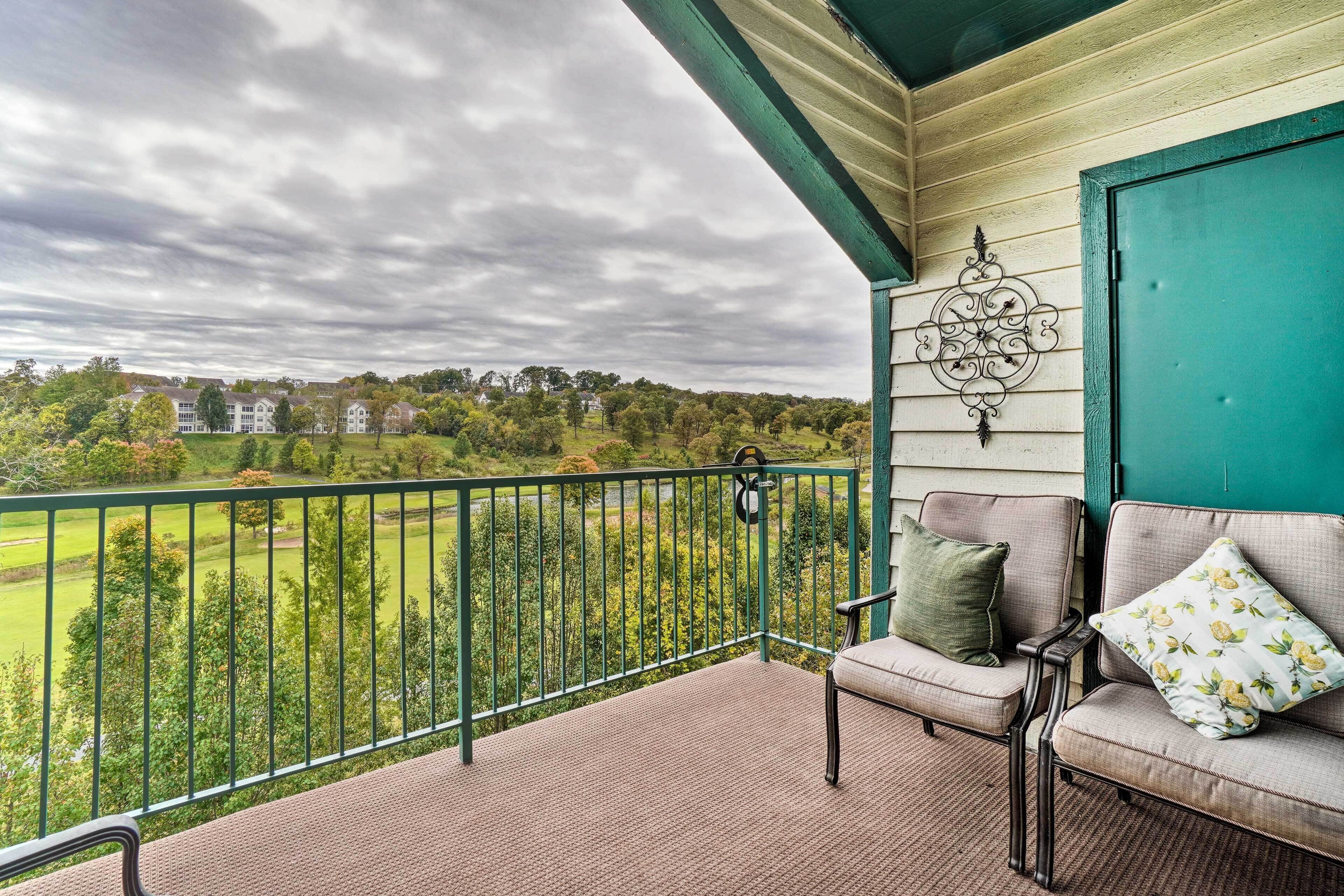 Ein Balkon mit Blick auf eine grüne Landschaft und Häuser.