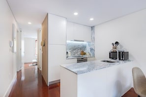 A modern kitchen with a marble countertop, a built-in microwave, and a sink. - 1BR with Private Patio | Porto Urban Flats (Porto)