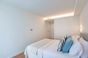 Ein Schlafzimmer mit einem Bett, Nachttischlampen und einer Tür zu einem anderen Raum.