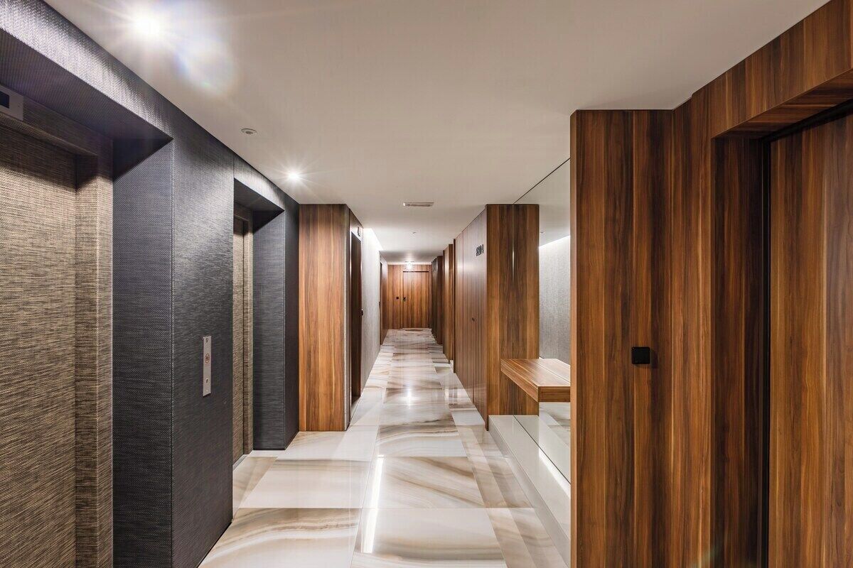 Un pasillo moderno con suelo de mármol, paneles de madera y varios portales.