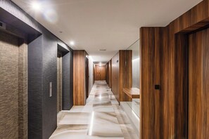 Un pasillo moderno con suelo de mármol, paneles de madera y varios portales.