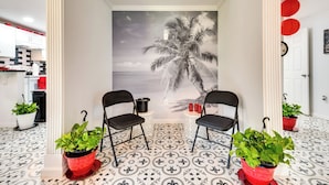 Ein Zimmer mit einer Palmenwandmalerei, zwei schwarzen Stühlen und Topfpflanzen.