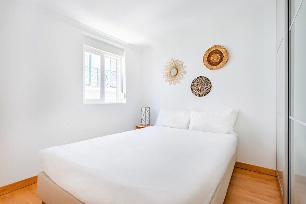 A bedroom with a large bed, a window, and wall decor.