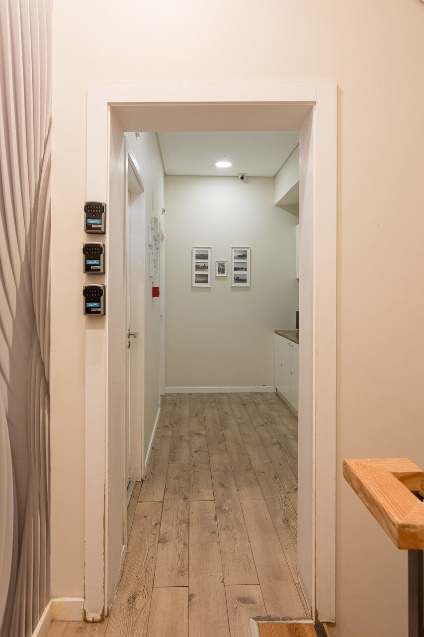 A hallway with wooden flooring, a door on the left, and a small table on the right.