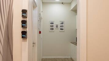 A hallway with wooden flooring, a door on the left, and a small table on the right.