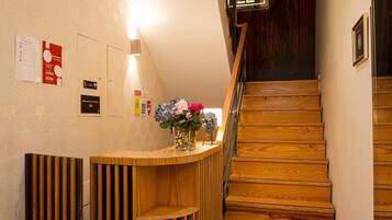 A reception desk with a wooden finish, a staircase with wooden steps, and a sign above the staircase.