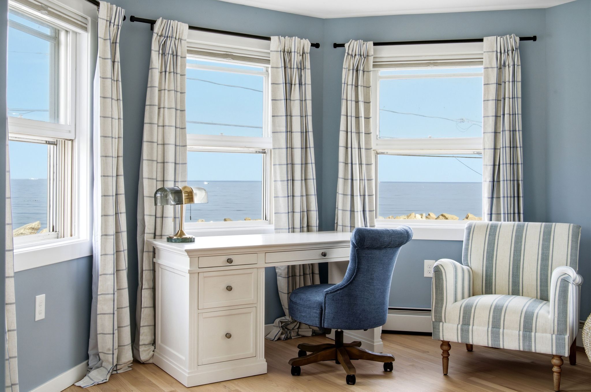 A room with a desk, a chair, and a view of the sea.