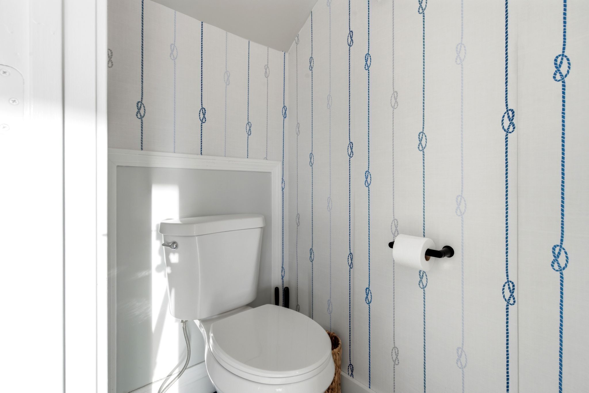 A bathroom with a toilet, a toilet paper holder, and a patterned wall.