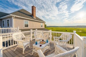 Een terras met rieten stoelen en een tafel, met uitzicht op een groen veld.