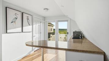 A modern kitchen with a curved countertop, a white cabinet, and a view of a house through a glass door.