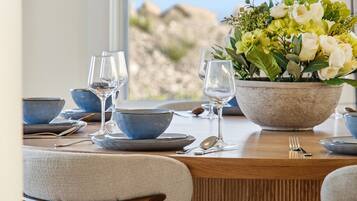 A dining table set with blue bowls, plates, and wine glasses, accompanied by a centerpiece of flowers.