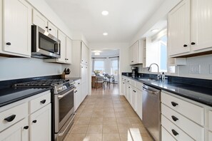 A kitchen with white cabinets, a stove, microwave, and a dishwasher.