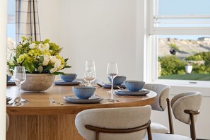 A dining table set with blue bowls, plates, and wine glasses, surrounded by chairs.