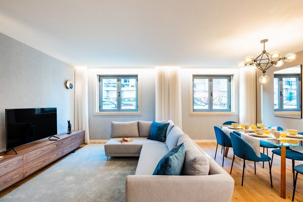Een moderne woonkamer met een televisie, bank, eettafel en stoelen.