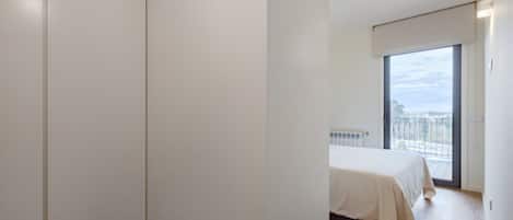 A bedroom with a bed, a radiator, and a large window with a view.