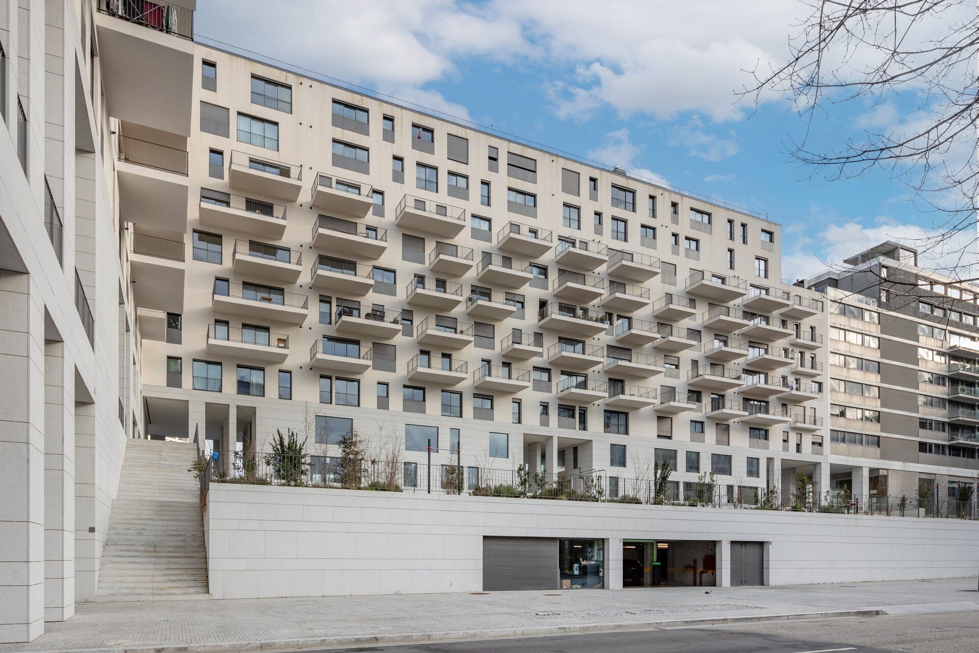 A modern multi-story residential building with balconies, a flat facade, and a clean, urban setting.